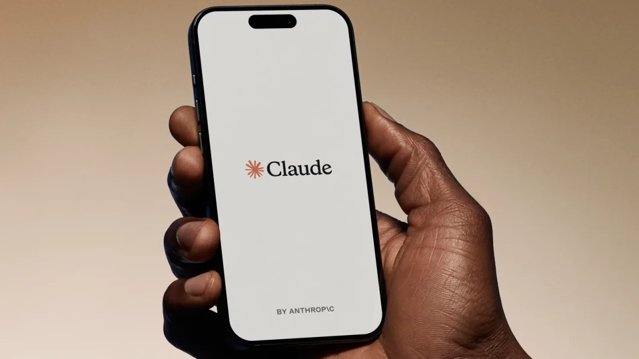 Bàn tay cầm điện thoại mở ứng dụng Claude.